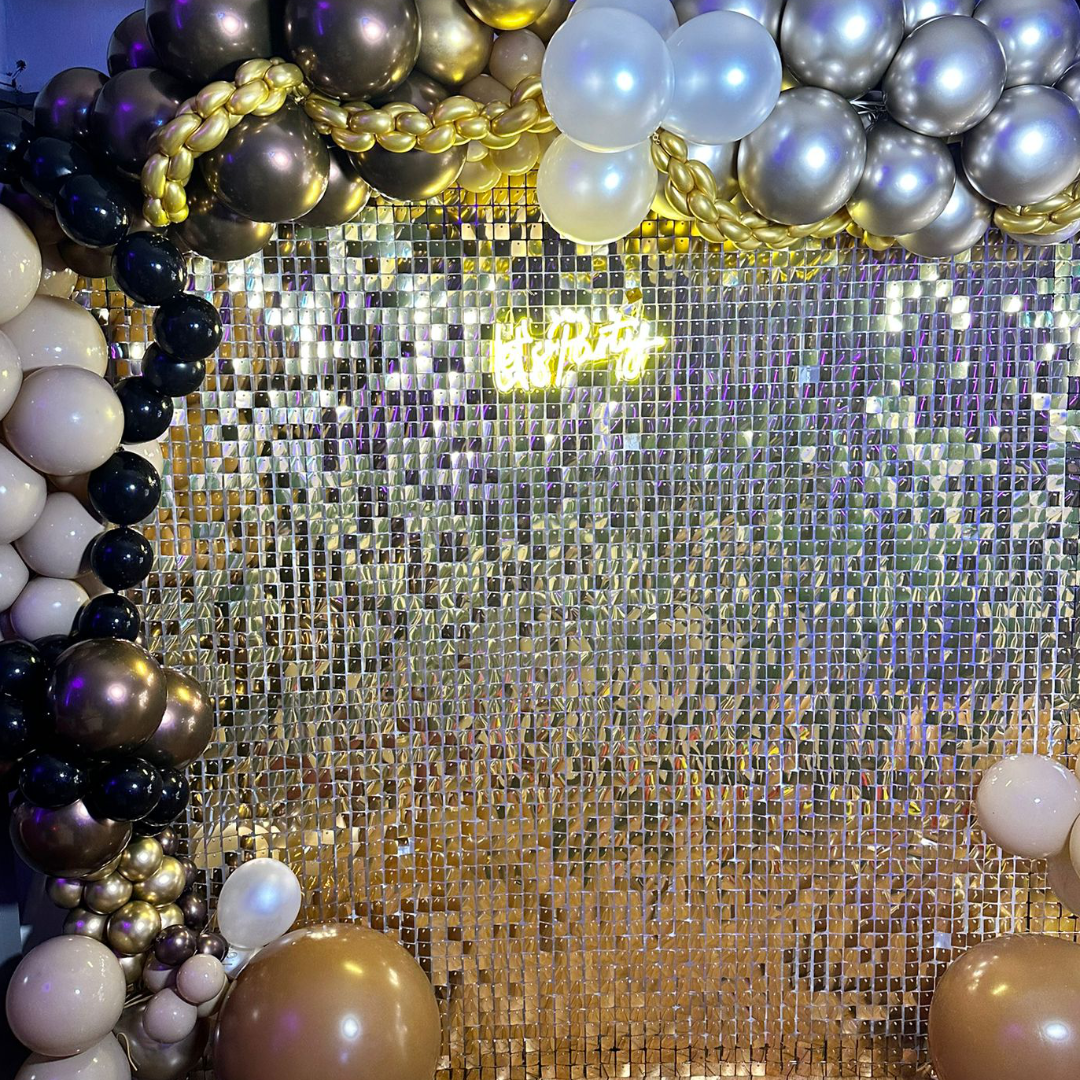 Gold glitter wall with neon sign and balloons